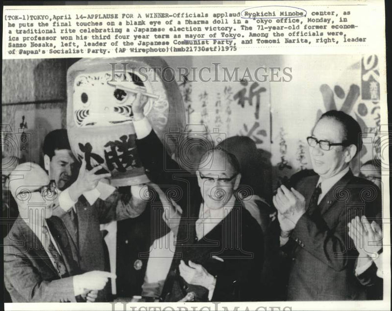 Load image into Gallery viewer, 1975 Press Photo Ryokichi Minobe touches blank eye of unfinished Dharma doll.
