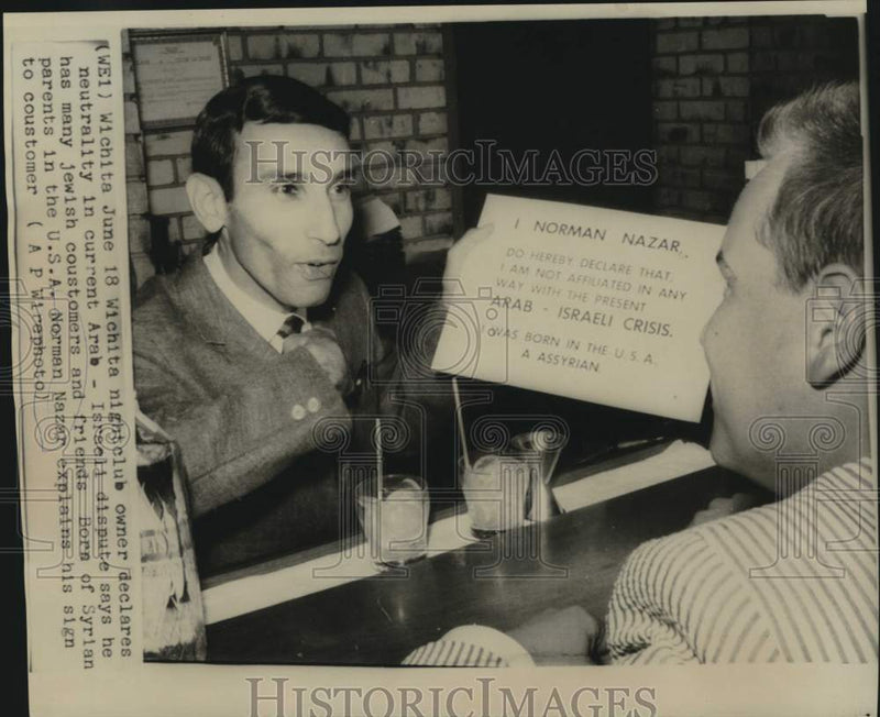 Load image into Gallery viewer, 1967 Press Photo Wichita nightclub owner Norman Nazar explains sign to customer
