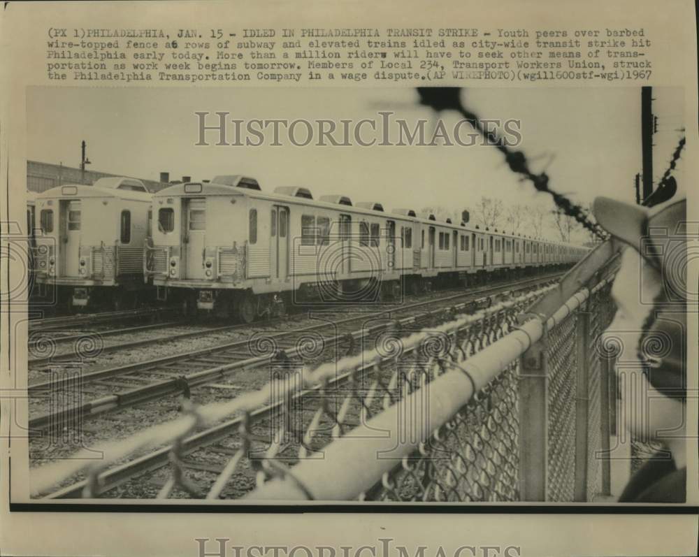 1967 Press Photo Youth peers over fence at idled subway and elevated trains