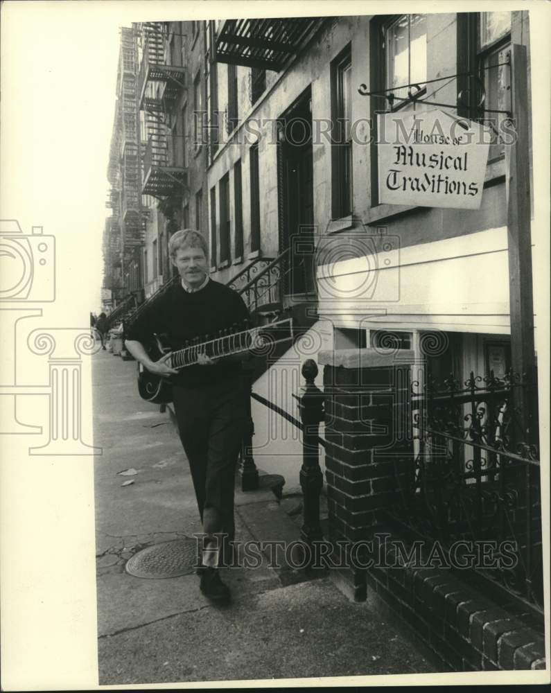 Load image into Gallery viewer, 1968 Press Photo Customer leaves House of Musical Traditions with sitar purchase
