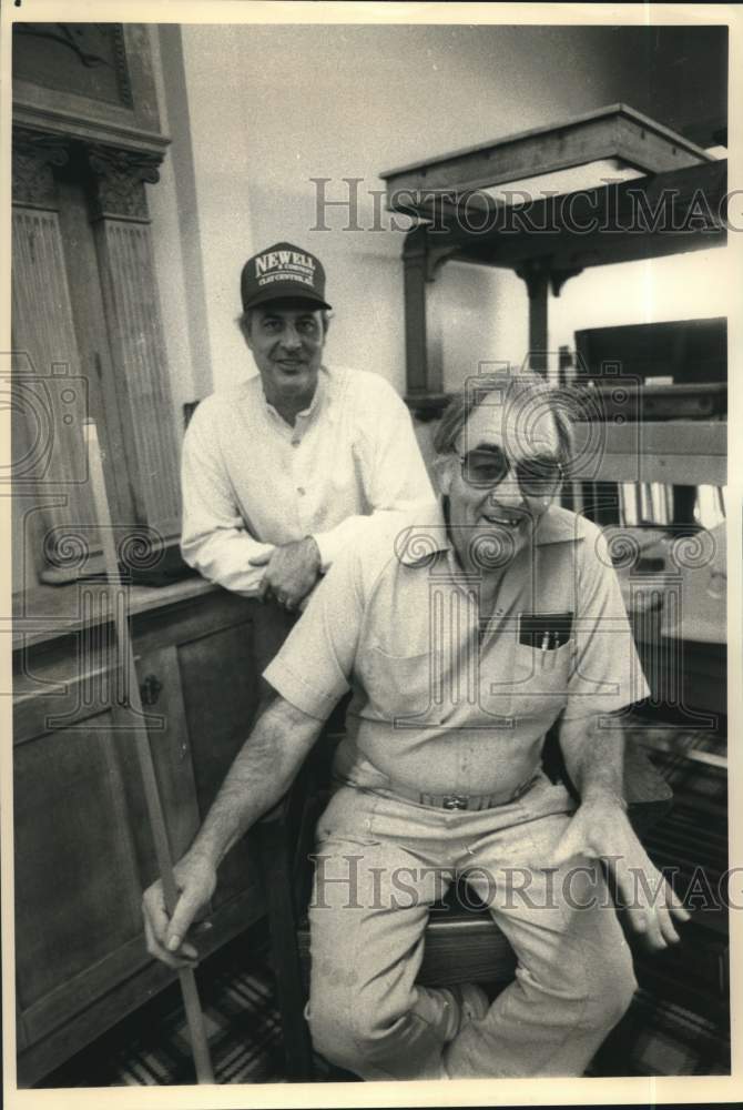 1988 Press Photo Pool table restorer Loyall Newell with cue as son watches