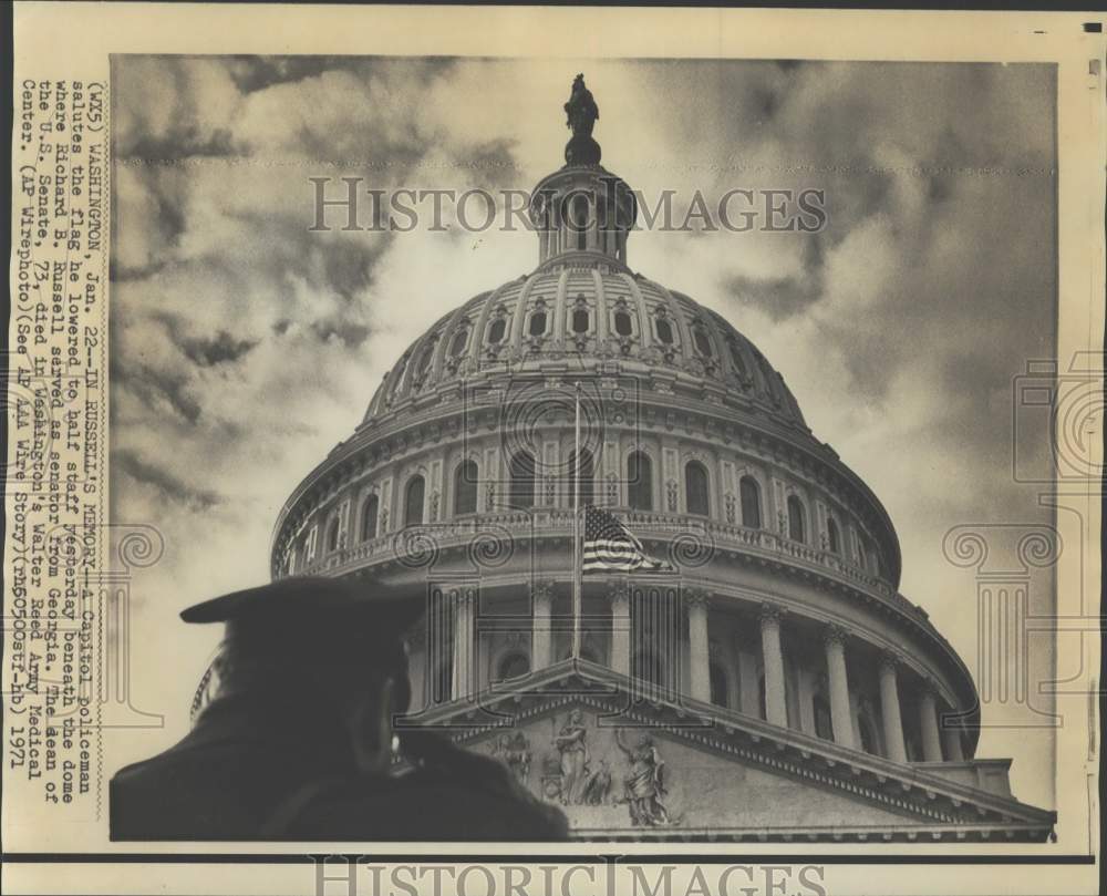1971 Press Photo A policeman salutes a flag honoring Sen. Richard Russell, Wash.