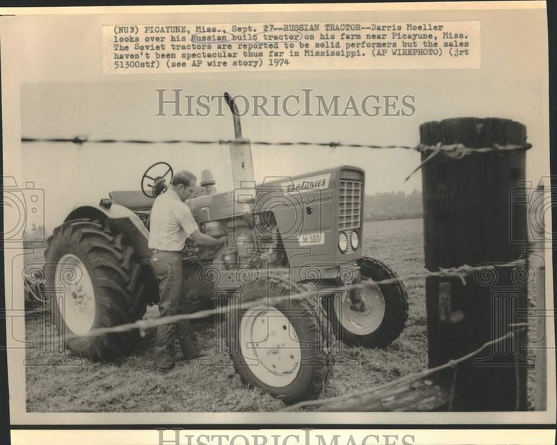 Load image into Gallery viewer, 1974 Press Photo Darris Moeller admires his Russian tractor on his farm, MS.
