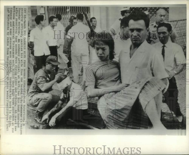 Load image into Gallery viewer, 1965 Press Photo Dick Robertson carries wounded wife from bombed embassy, Saigon
