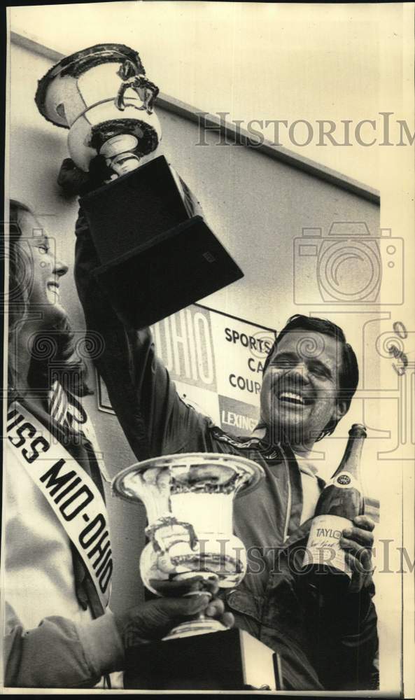 1973 Press Photo Car Racer Mark Donohue Lifts Trophy with Bottle of Champagne- Historic Images