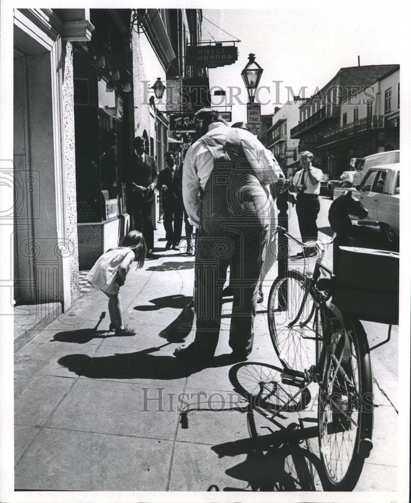 1970 Press Photo Girl watching man sweep Bourbon Street, New Orleans, Louisiana