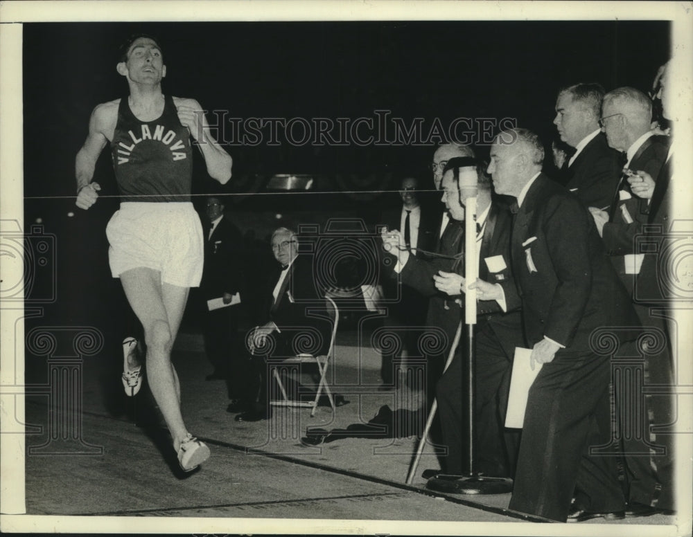 1958 Press Photo Ron Delany speeds across Finish Line and Officials track Time