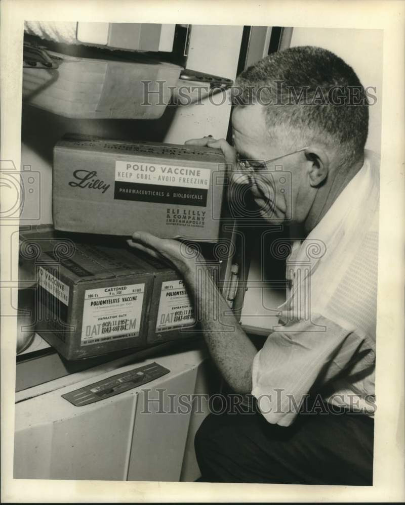 Load image into Gallery viewer, 1957 Press Photo Jack Morse checking Polio vaccine supplies in his refrigerator
