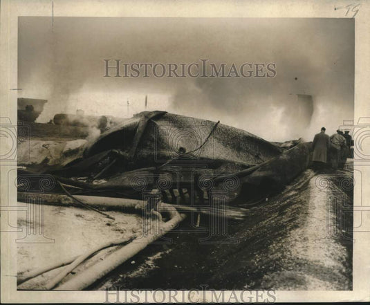1957 Press Photo Collapsed storage tanks, firemen and oil workers after fire