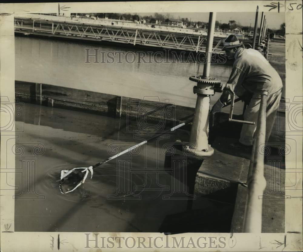 1948 Press Photo N. Saune is skimming debris off top of water coming into plant.