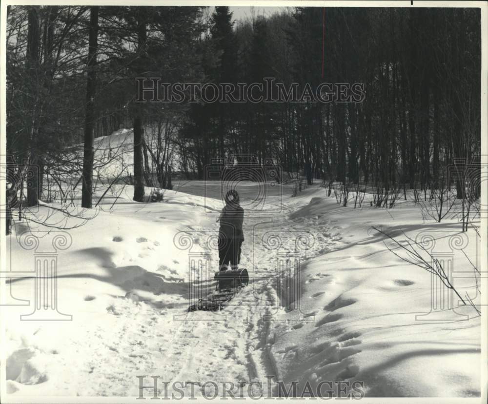 1976 Press Photo Kid drags a toboggan during winter in Canada - pia02319- Historic Images