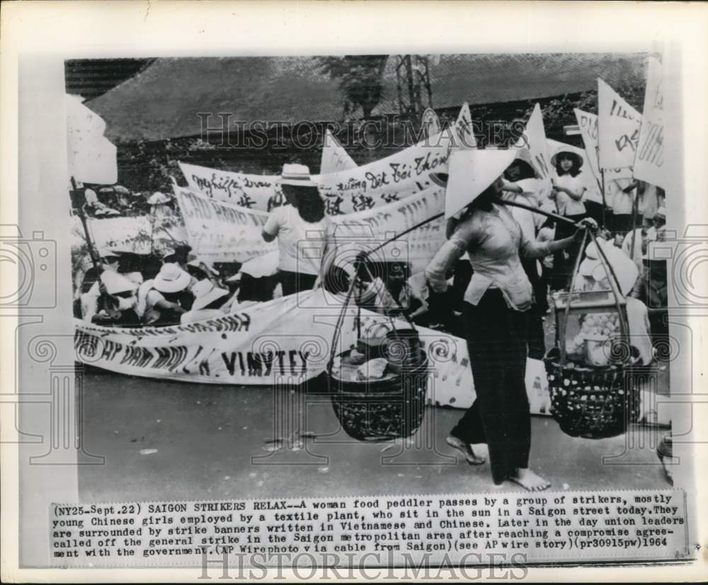 1964 Press Photo Food peddler walks past striking Vietnamese workers in Saigon