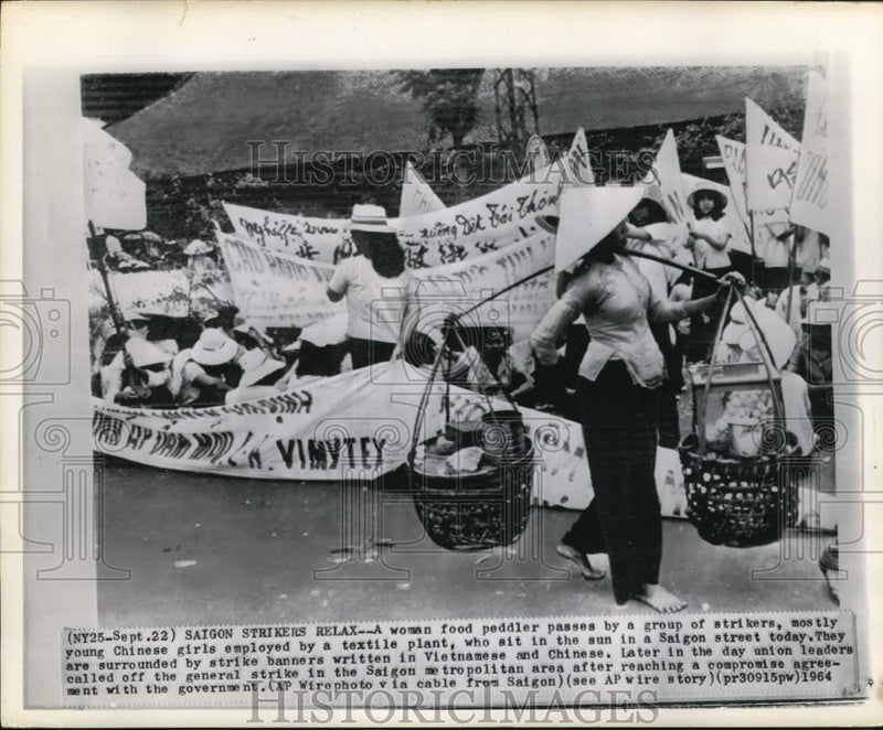 Load image into Gallery viewer, 1964 Press Photo Food peddler walks past striking Vietnamese workers in Saigon
