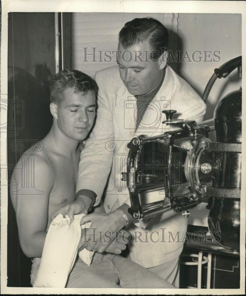 1951 Press Photo Football player Don Heinrich treated by physician John W Geehan- Historic Images