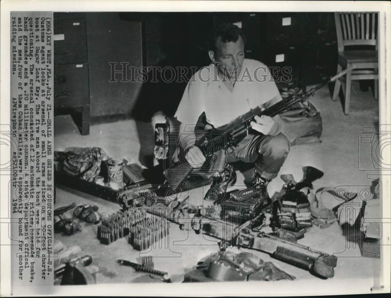 Load image into Gallery viewer, 1964 Press Photo US Customs agent with confiscated weapons from boat in Florida
