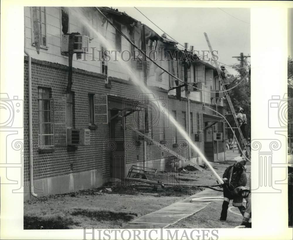 1988 Press Photo Fireman put water on smoldering remains of apartment fire, TX- Historic Images