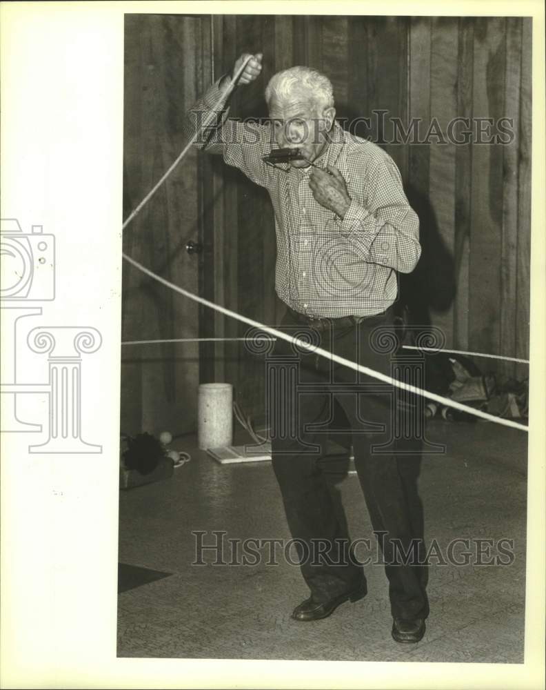 1983 Press Photo Entertainer Hamilton Floyd plays harmonica while lassoing- Historic Images