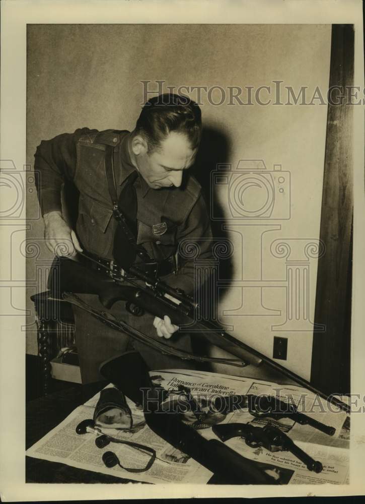 Press Photo Man Cleans Rifle With Three Guns on Table - sas20975- Historic Images