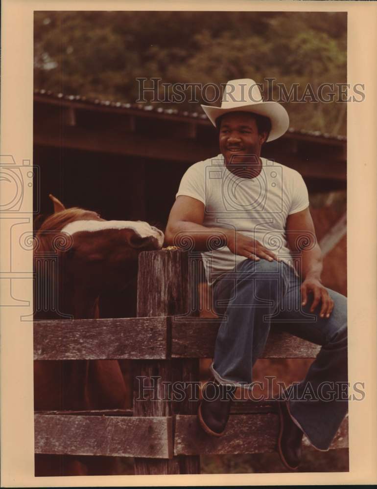 Press Photo Boxer George Foreman Sits on Fence, Feeds Horse - sas22739- Historic Images