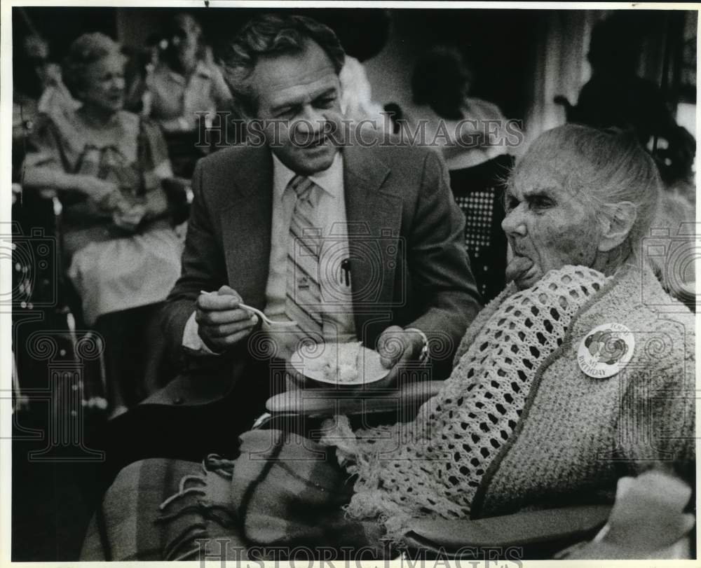 1987 Press Photo Glenn Brown offers a cake to Lena Medlin at Morningside Manor- Historic Images