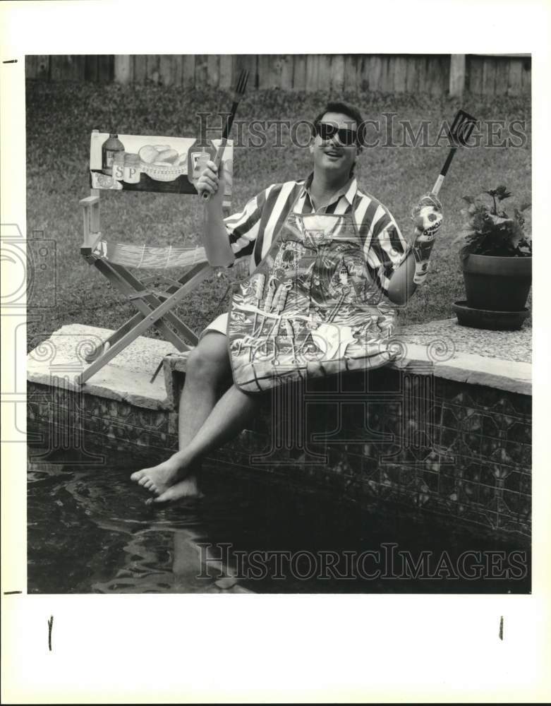 Press Photo Getting ready to cook for barbecue, holding tools - sax23170- Historic Images