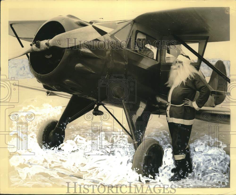 Press Photo A man dressed as Santa Claus poses with an aeroplane - sax23530- Historic Images