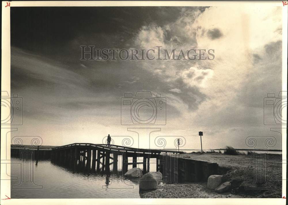 1976 Press Photo A lone figure crosses a Chappaquiddick Island wooden bridge- Historic Images