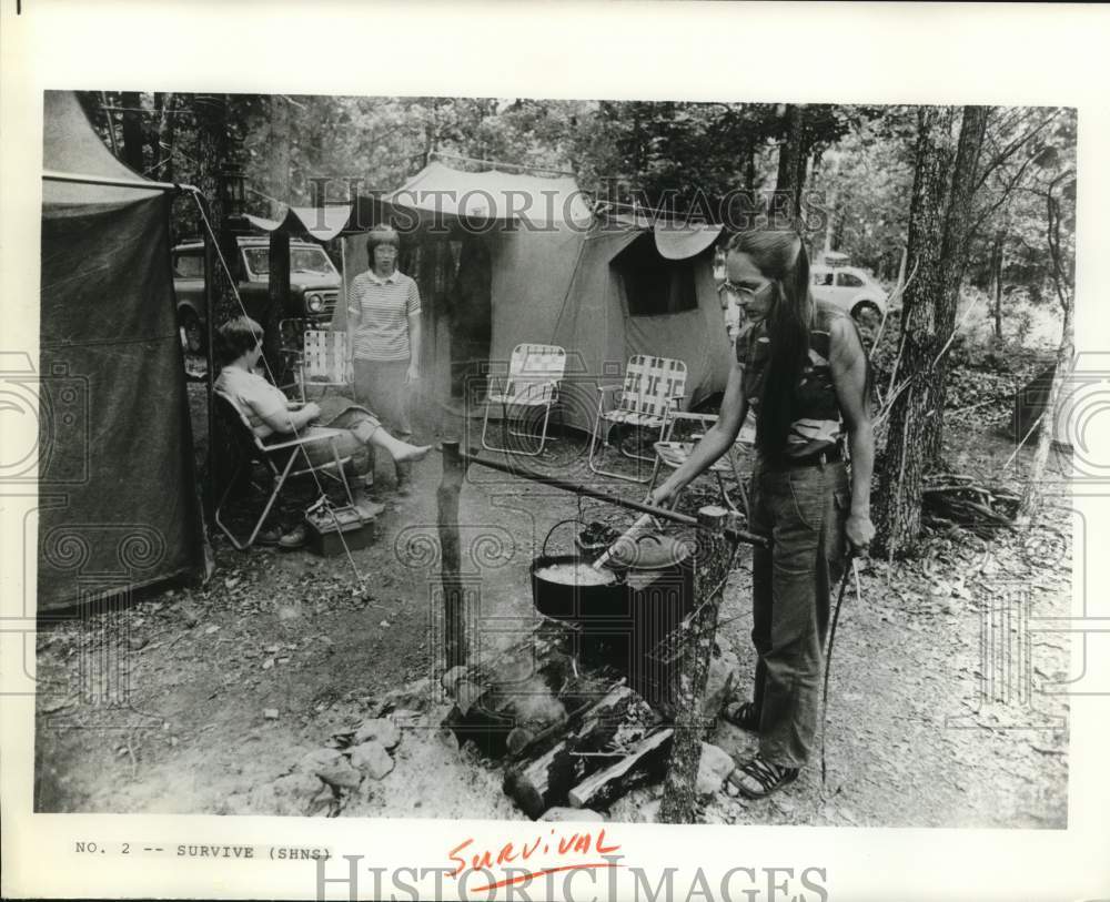 Press Photo Young adults shown relaxing and cooking meal at survival camp site- Historic Images