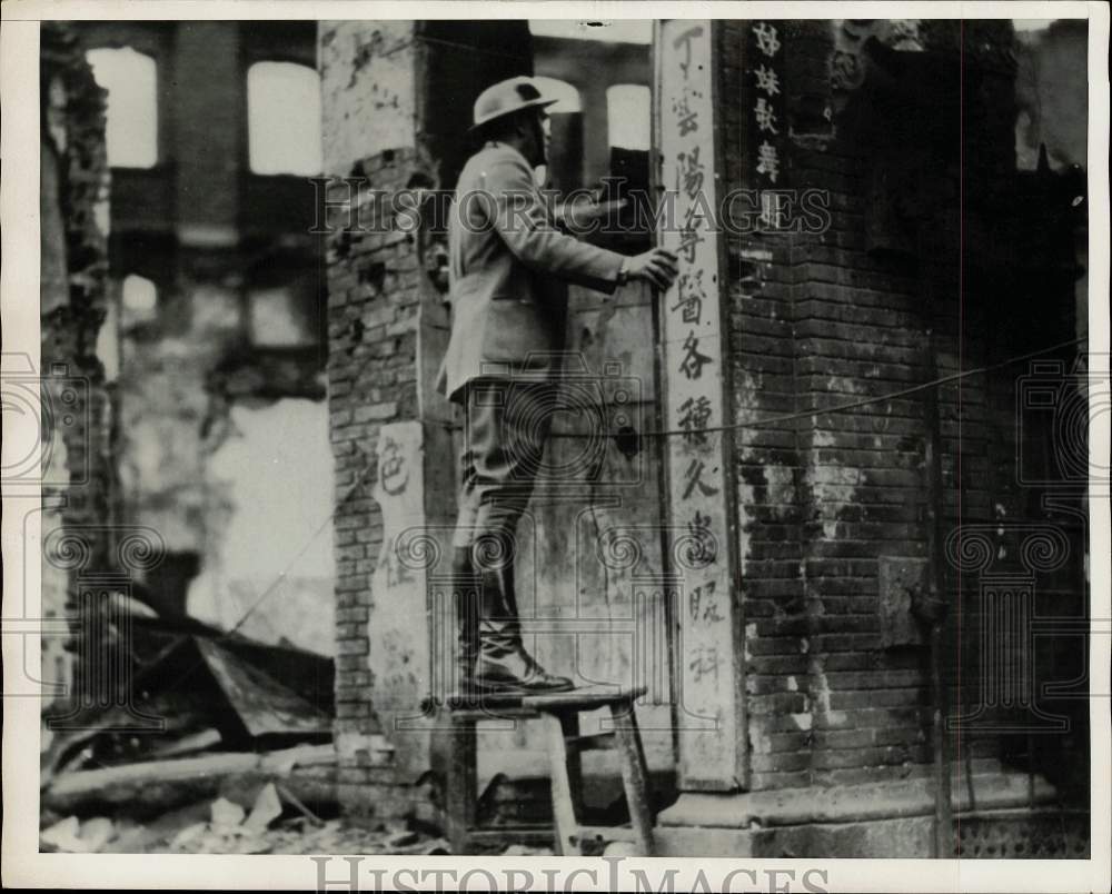 Press Photo Man inspects damage to Building with Asian Writing on the side