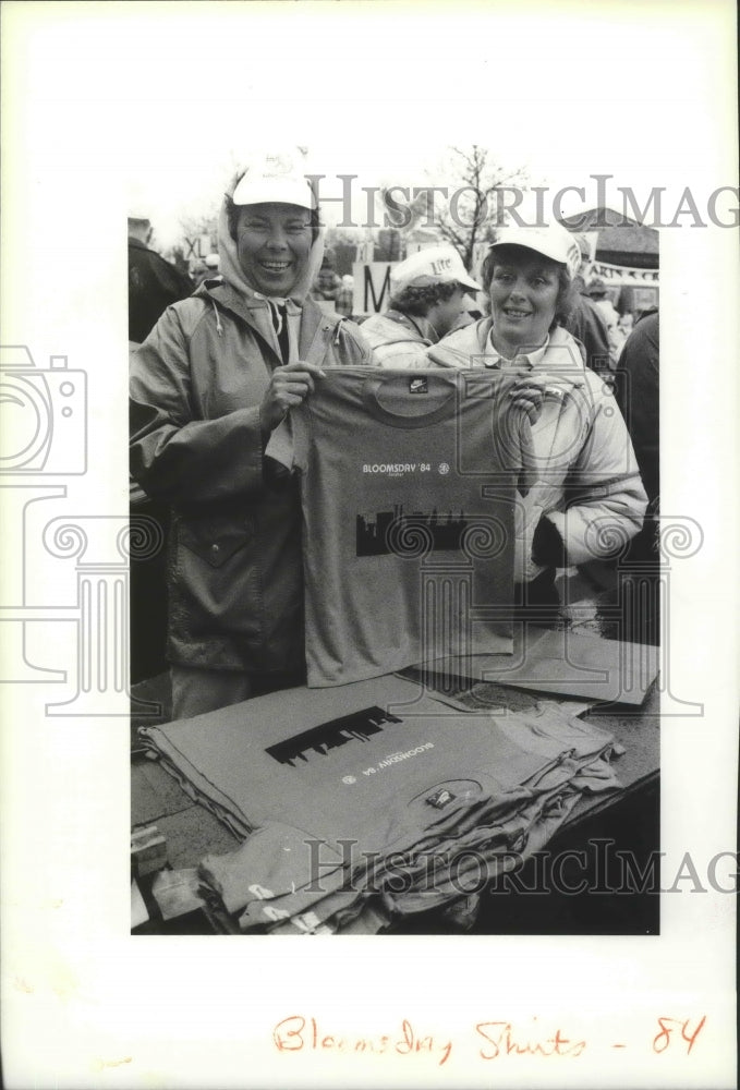 1984 Press Photo Two workers hold up a t-shirt featuring the Bloomsday 1984 logo- Historic Images