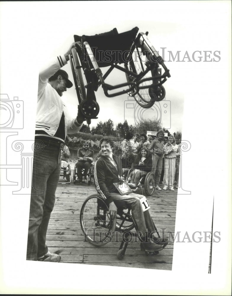 1984 Press Photo Jerry Martin Sits as Other Man Lifts a Wheelchair On Bloomsday- Historic Images