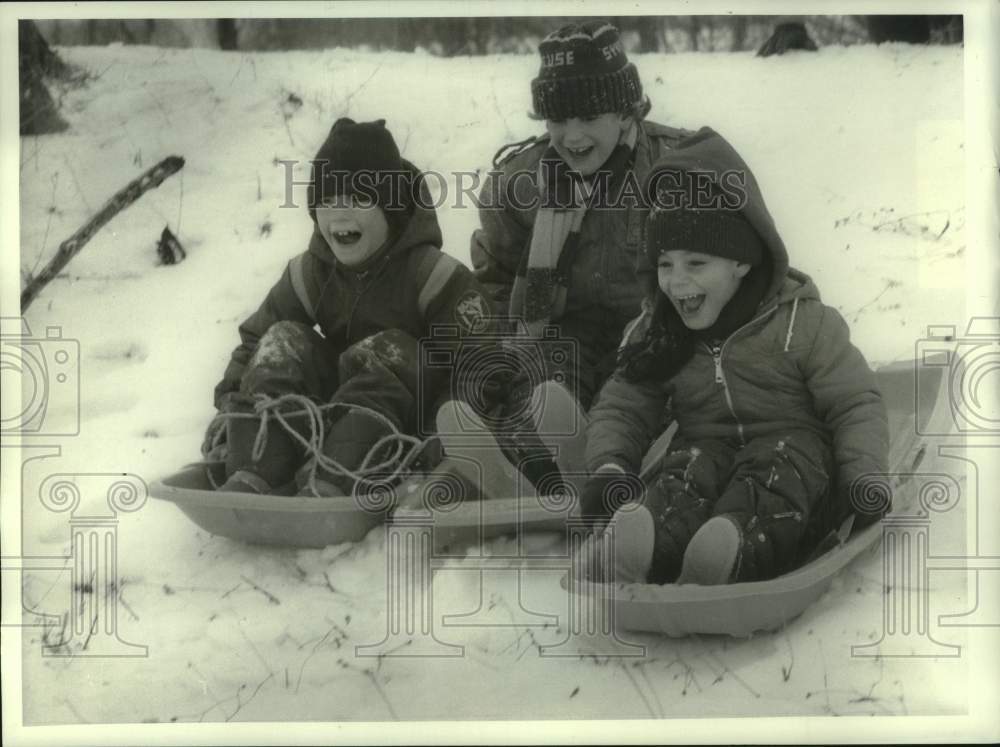 1986 Press Photo Friends Snow Sledding at Cedar Bay Park in DeWitt for Canal Day- Historic Images