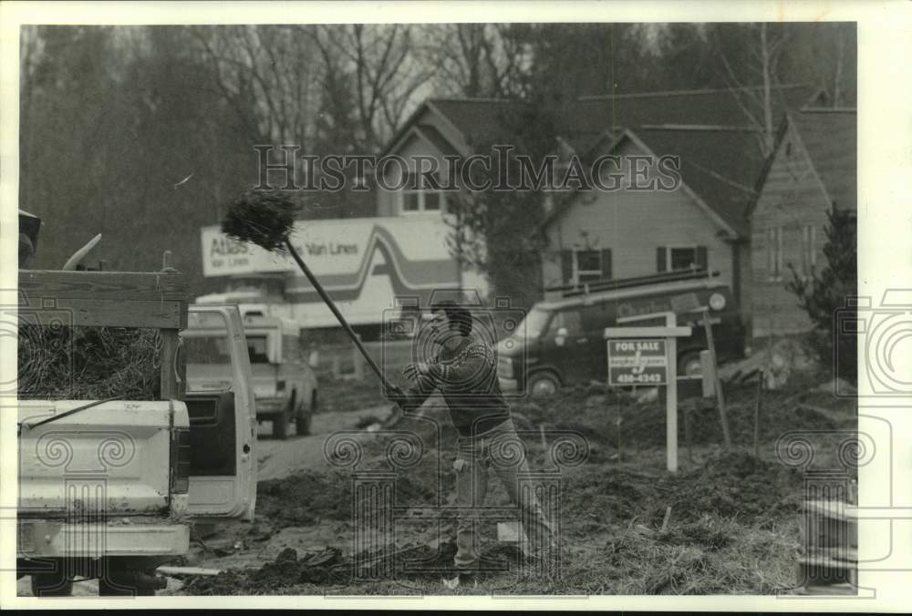 1988 Press Photo Meele Construction Worker Picks Up Straw From Lawn, Liverpool- Historic Images