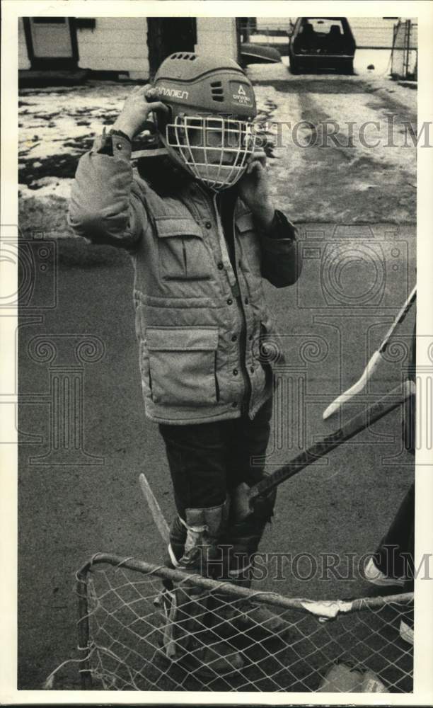 1986 Press Photo Kirby Lord adjusts Hockey Mask, Game in Liverpool, New York- Historic Images