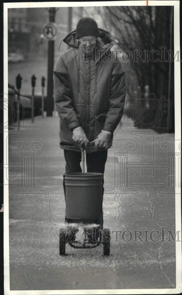 1987 Press Photo Al Connell spreading salt on Sidewalk on Auburn, New York- Historic Images