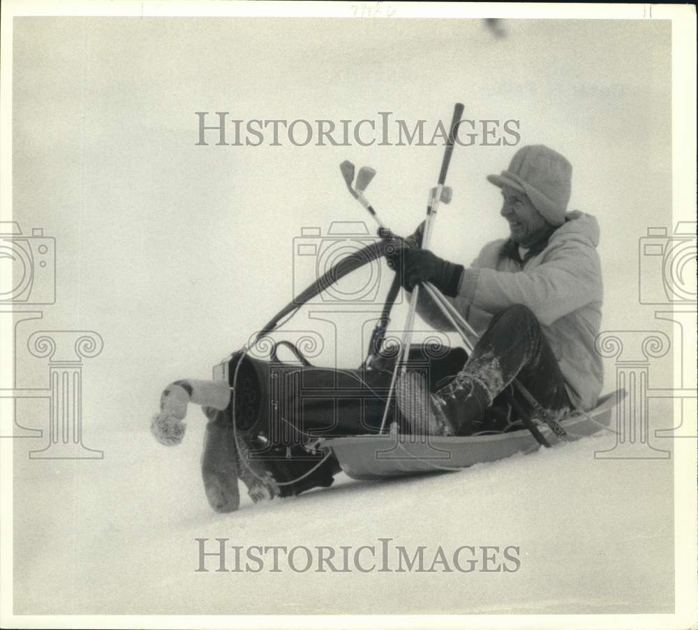 1986 Press Photo Hank Goldacker in Sled with Golf Clubs in Snow - sya86220- Historic Images