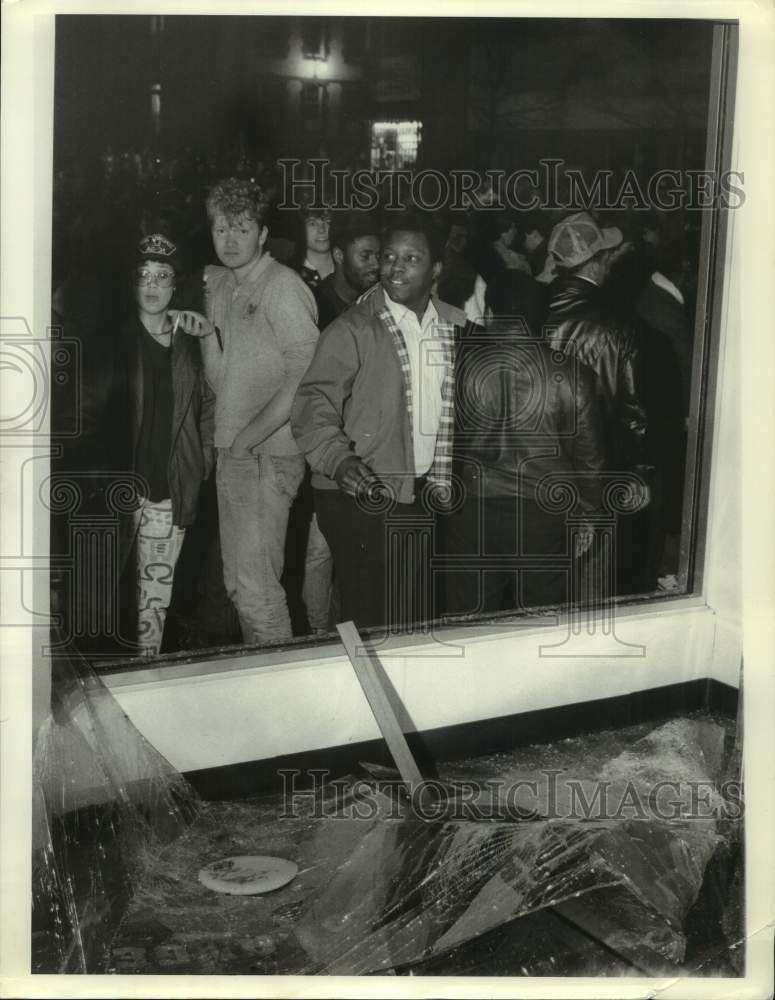 1987 Press Photo SU NCAA. Fans look over the damage done to store window- Historic Images