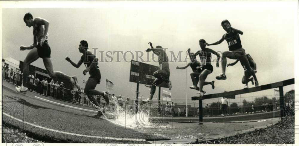 1988 Press Photo Runners leap over hurdle & land in water during Steeplechase- Historic Images