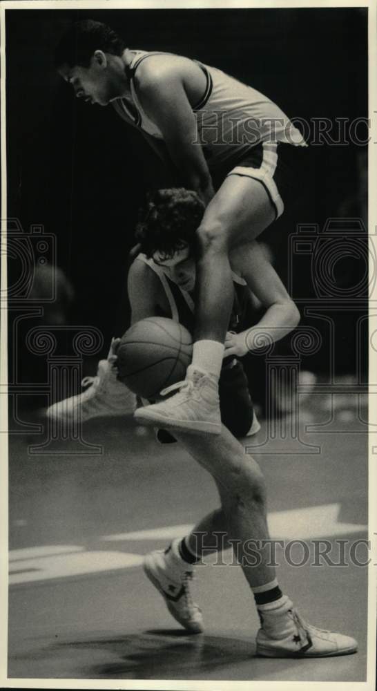 1984 Press Photo Basketball player dribbles as defender lands on his shoulders- Historic Images