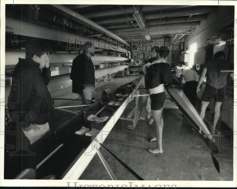 1985 Press Photo Crew members look over their boat inside the boathouse- Historic Images