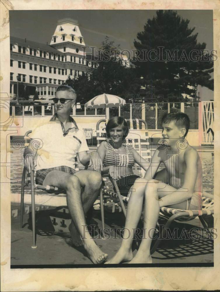 Load image into Gallery viewer, 1966 Press Photo Edgar A. Sandman sits by pool with wife and son at resort
