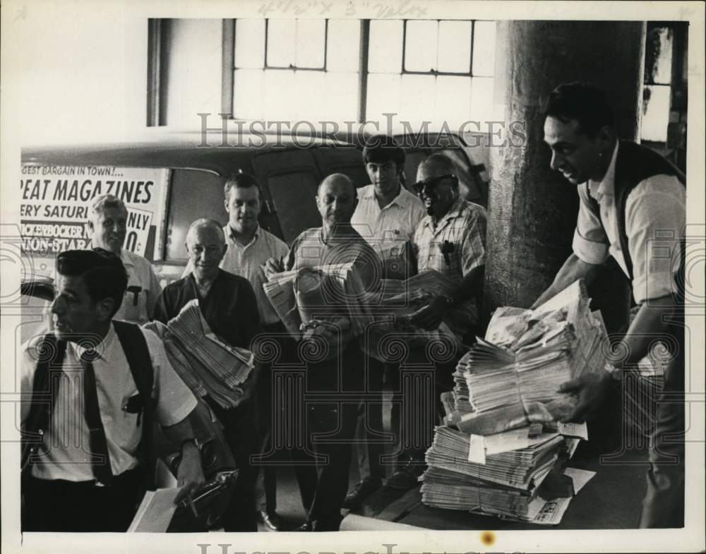 1969 Press Photo Julius Padula hands out bundles of newspapers to men lined up
