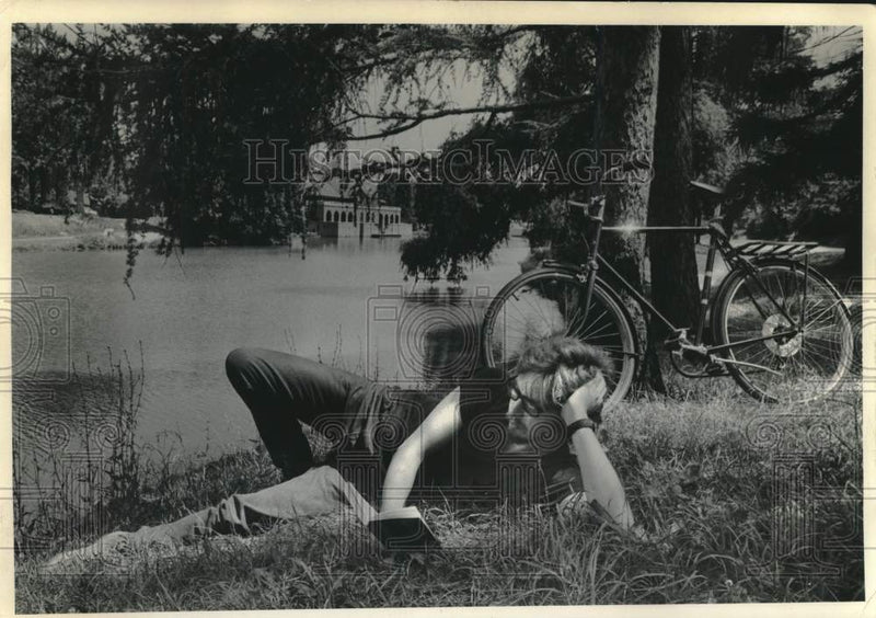 Load image into Gallery viewer, 1971 Press Photo Man reads book, bicycle parked against tree at Washington Park
