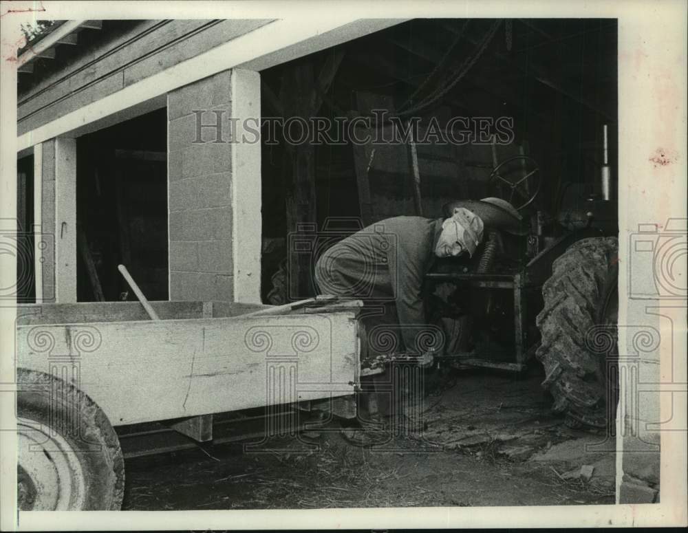 1975 Press Photo Luzerne Shafer attaches trailer to old tractor in garage- Historic Images
