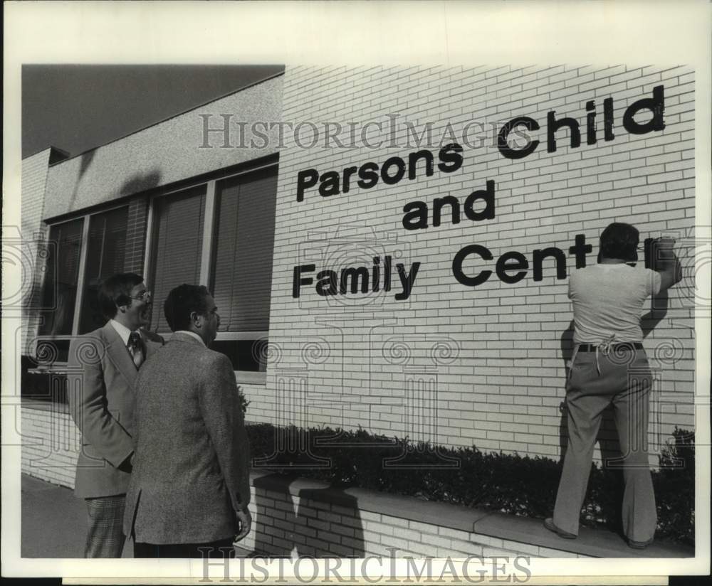 1978 Press Photo Officials watch work hang Parsons Family Center sign, New York