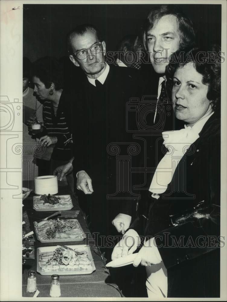 Load image into Gallery viewer, 1977 Press Photo Brother Augustine Loes, Jim Coyne &amp; Sue Coyne get food at event

