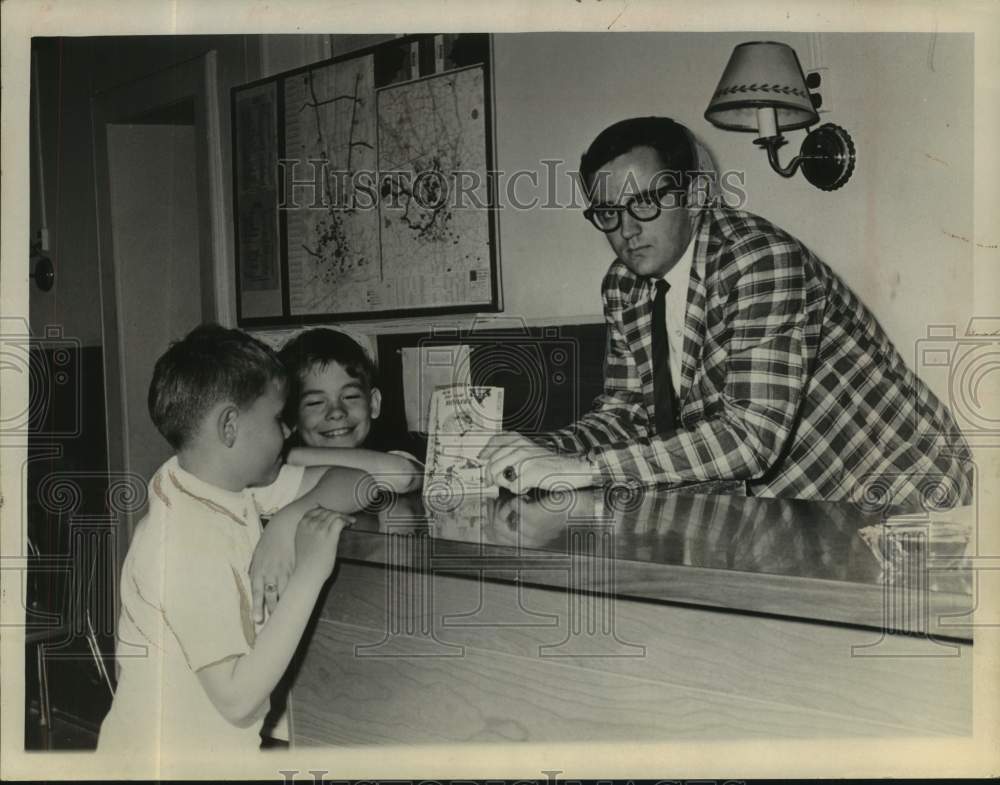 1966 Press Photo Paul C Maguire shows an items to two young boys behind counter- Historic Images