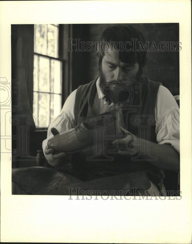 1980 Press Photo Cobbler examines shoe at Old Sturbridge Village, Massachusetts- Historic Images