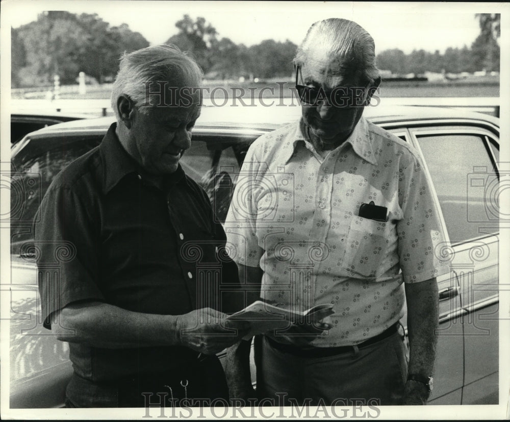 1980 Press Photo Men look over race program at Saratoga Raceway in New York- Historic Images