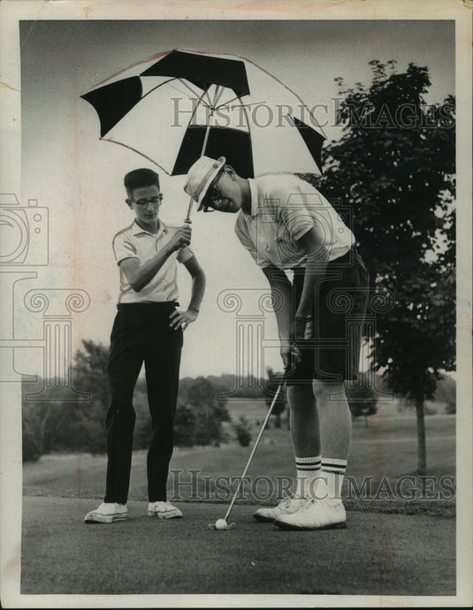 Press Photo Golfer Charlie Murphy puts on green as young man holds umbrella- Historic Images